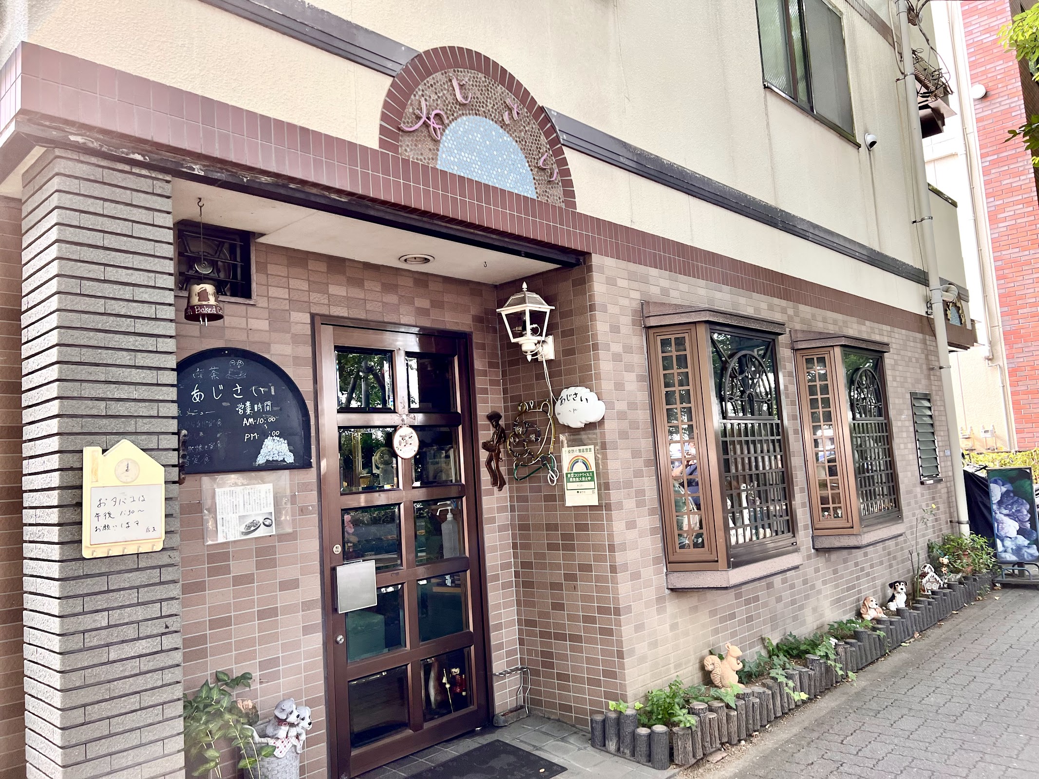 茶色タイル張りの外壁に「あじさい」の文字看板、入口扉周りに小物や犬の置物が並ぶ喫茶店正面