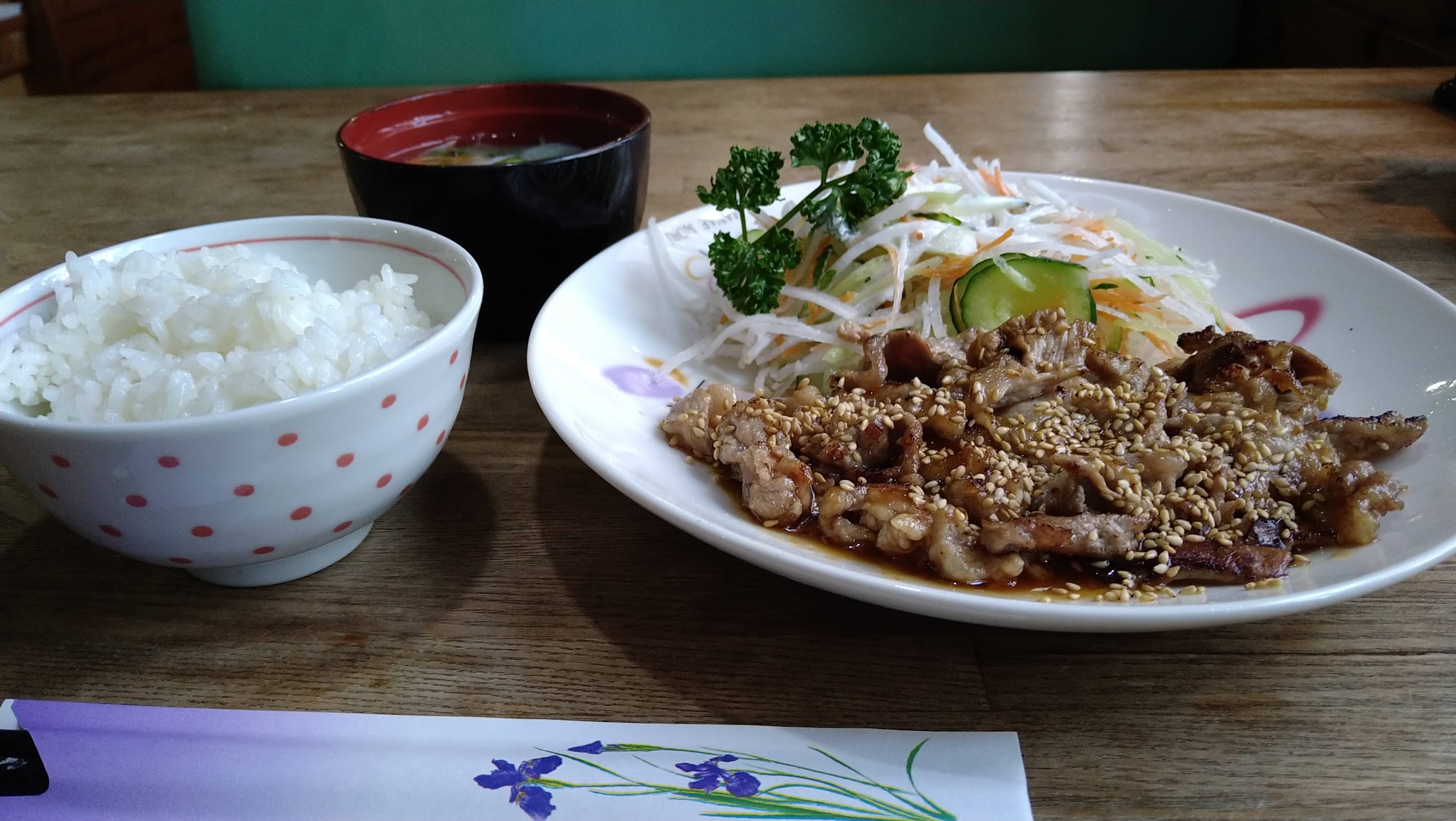 白い花柄皿にのった生姜焼き定食・ドット柄茶碗のご飯・赤い椀の味噌汁